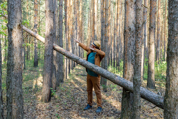 a man in a hat near a tree blocking his path makes a movement with his hands towards the shaft
