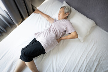 Upset asian senior woman holding hips or waist with her hand while rest in bed,painful facial...