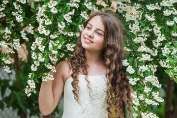 Beautiful girl long curly hair spring flowers background, full bloom concept