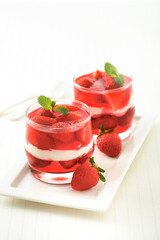 Strawberry juice with yogurt and strawberry in glasses put on white plate, vertical view.