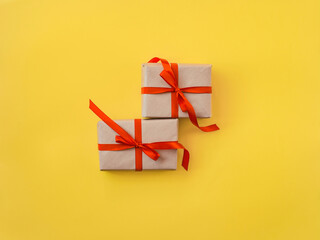 Gifts decorated with red ribbon, yellow background, copy space. Two present boxes, top view. Valentine or love, spring holidays, Christmas and birthday concept.