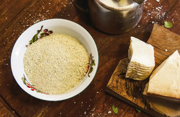 Grated cheese in a ceramic bowl on a rustic wooden board.