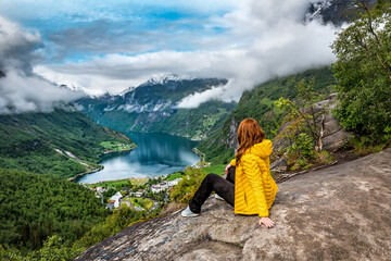 Woman in yellow sitting over Geiranger fjord