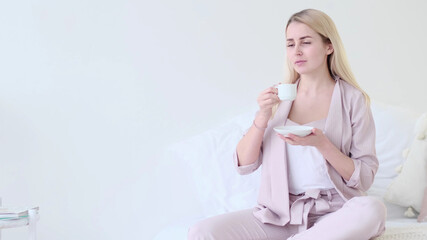 beautiful young woman with cup of coffee in a romantic setting. Front view woman with coffee cup looking at camera sitting on a couch. selective focus.