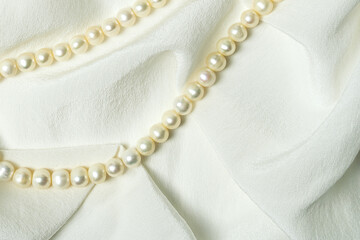 Romantic elegant white background with natural pearls on top quality silk fabric.