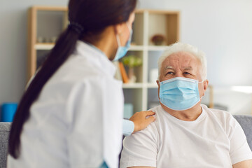 Mature elderly man patient in medical mask getting support of woman doctor