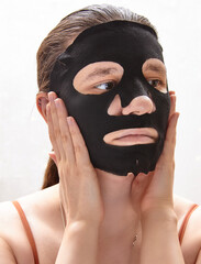 Young woman with sheet facial mask on white background. Skin care healthcare cosmetic procedures concept. 