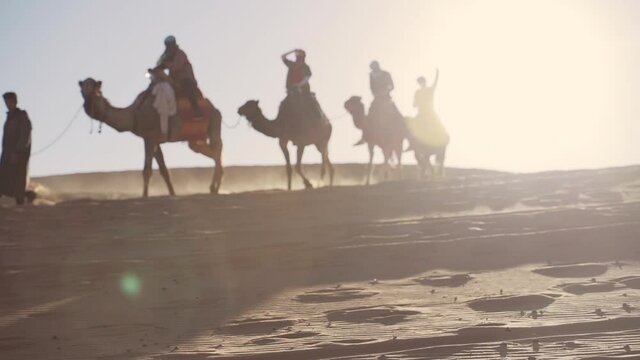 Tourists Riding Camels Under Bright Sun In Desert