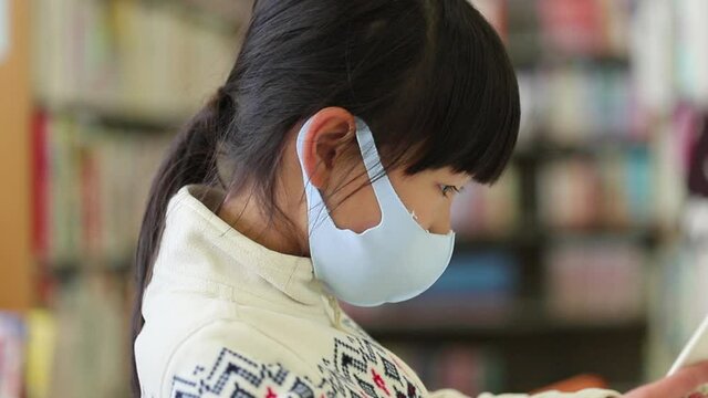 図書館で本を読んでいる可愛い子供の姿