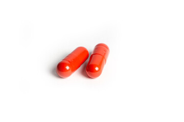 Three Red Pills Capsules with Many in Background Isolated on a White