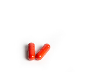 Three Red Pills Capsules with Many in Background Isolated on a White