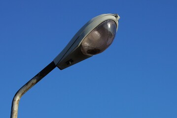 one old gray lantern on an iron pole on the street against a blue sky