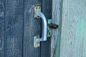 white old door handle with lock on the gray wooden door
