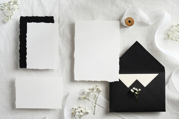 Elegant set of wedding stationery top view. Flat lay blank paper cards, black envelopes, flowers,...