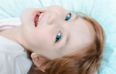 Cheerful child with smile on his face lies on pillow before bed.