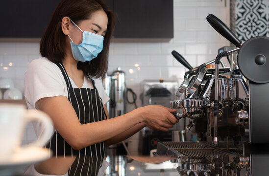 Asian Barista Woman Wearing Face Masks To Prevent Contagious Diseases And Brewing Coffee In The Coffee Shop. The Concept Of Prevention From COVID 19