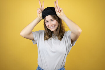 Beautiful young caucasian girl wearing french look with beret over isolated yellow background Posing funny and crazy with fingers on head as bunny ears, smiling cheerful