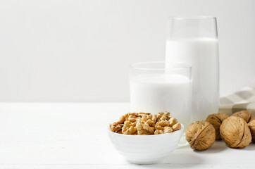 Milk from walnuts and nuts on a white wooden background. Products containing vegetable protein, vitamins, and useful amino acids. Copy space.