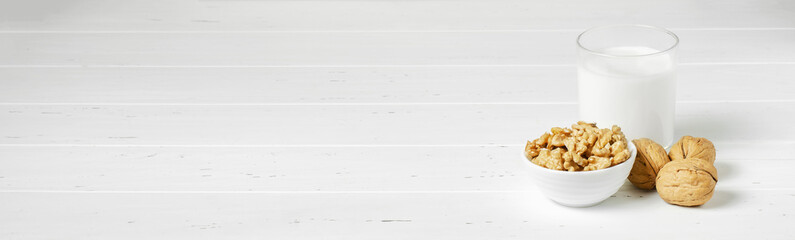 Milk from walnuts and nuts on a white wooden background. Products containing vegetable protein, vitamins, and useful amino acids. For a healthy and vegetarian diet. Copy space.