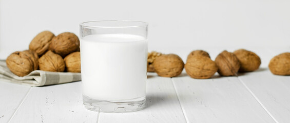 Milk from walnuts and nuts on a white wooden background. Products containing vegetable protein, vitamins, and useful amino acids. Copy space.