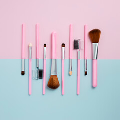 Set of fashion makeup brushes on pastel pink and blue background. Beauty cosmetic makeup product layout. Creative fashionable concept. Cosmetics make-up brushes collection, flat lay, top view.