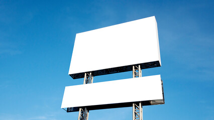 Large billboard blank for design sits on the roadside, with a bright blue sky in the background..