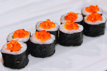 Sushi rolls with fish, caviar, creamy sauce, avocado, on a white plate
