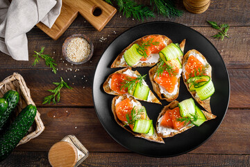 Toasts with salted salmon fish, ricotta cheese, fresh cucumber and ciabatta bread