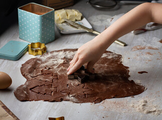 Children's hands carve cookies from chocolate dough