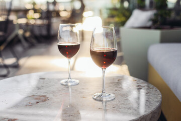Two glasses of red wine on a restaurant luxury terrace, sunset light