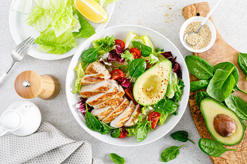 Grilled chicken meat and fresh vegetable salad of tomato, avocado, lettuce and spinach. Healthy and...