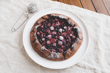 Delicious freshly baked vegan almond berry galette on wooden rustic background, top view. Sweet food, summer dessert.