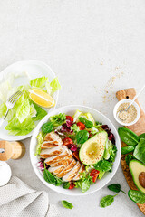 Grilled chicken meat and fresh vegetable salad of tomato, avocado, lettuce and spinach. Healthy and detox food concept. Ketogenic diet. Buddha bowl dish on white background, top view