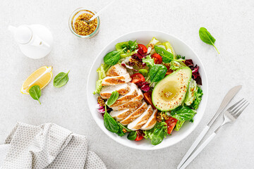 Grilled chicken meat and fresh vegetable salad of tomato, avocado, lettuce and spinach. Healthy and detox food concept. Ketogenic diet. Buddha bowl dish on white background, top view - 403605530