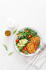 Grilled chicken burgers, avocado and fresh vegetable salad with tomato and arugula, top view