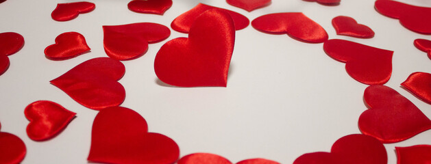 Red heart among a large number of hearts scattered on a white background.