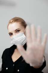 Young blong woman in white medical mask and transparent gloves showing STOP sign with hand. Prevention coronavirus Covid-19 on quarantine period. Ð¡osmetologist, beautician in mask. New reality