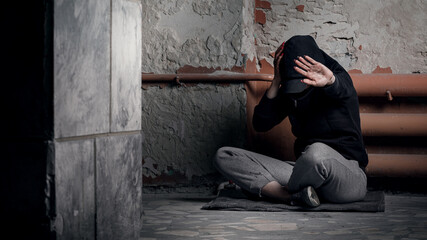 The concept of drug addiction and homelessness. A depressed and hopeless woman sits after using...