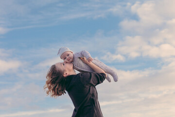 Fototapeta na wymiar A young woman and a baby playing outdoors, blue sky