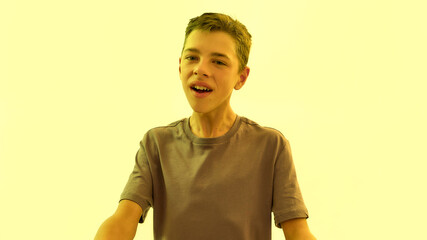 Portrait of teenaged disabled boy with cerebral palsy looking at camera isolated over yellow light...