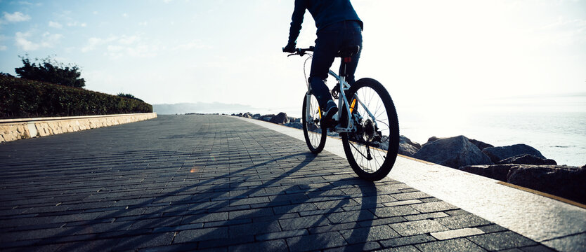 Cyclist riding bike in the sunrise coast path