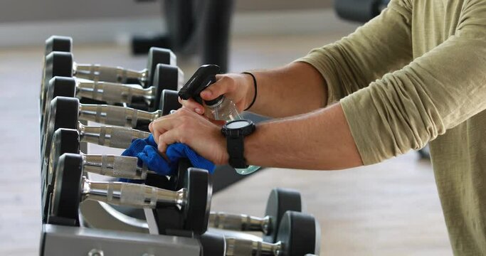Fitness staff cleaning exercise machines alcohol sanitizer spray at the gym. preventive disease of the Covid 19 virus