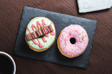Overhead view of two colorfull donuts on board plate
