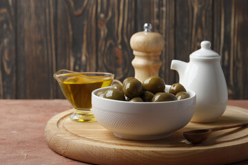 Composition of green olives in oil, olive branch, gravy boat on the background. Space for text.