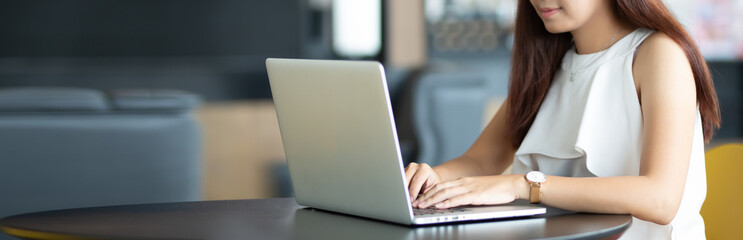 Closeup of business lady working at the table with laptop. Loft office, researching new business strategy. Wide screen panoramic