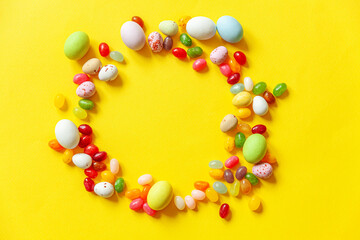 Happy Easter concept. Preparation for holiday. Easter candy chocolate eggs and jellybean sweets isolated on trendy yellow background. Simple minimalism flat lay top view copy space.