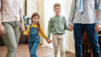 Happy family. Children and grandparents holding hands while standing at home, smiling at camera