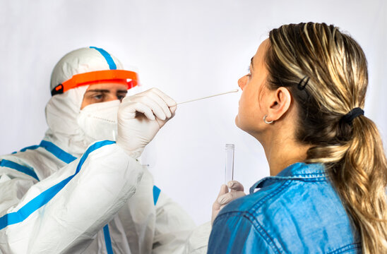 Physician wearing personal protective equipment performing a COVID-19 PCR test, patient nasal swab sample for PCR DNA diagnostic procedure.