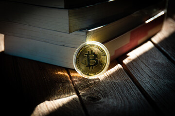 A golden coin was placed on a piece of wood with a number of books. Bitcoin symbol.