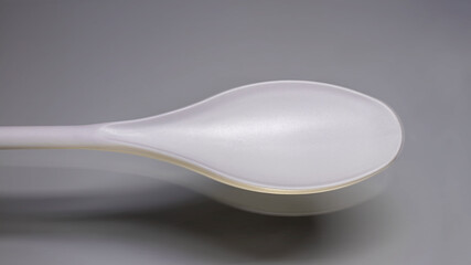 White plastic spoon or ladle close-up on a gray background